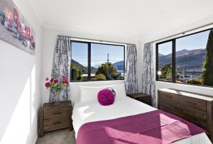 皇后镇The Gables - Queenstown - Beautiful, stylish, newly renovated 4 bedroom home的一间卧室配有一张带紫色枕头和窗户的床