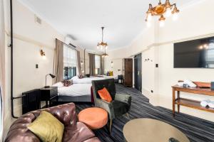 昆比恩Hotel Queanbeyan Canberra的酒店客房设有一张沙发和一张床