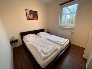 伯尔格伦德-雷特维施Leuchtfeuer Fewo "Kimberly"的一间卧室配有一张带白色床单的床和一扇窗户。