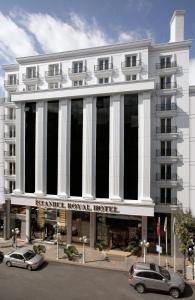 伊斯坦布尔伊斯坦布尔皇家酒店的一座白色的大建筑,前面有汽车停放