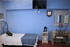 莫哈卡尔阿科广场旅馆的一间卧室设有蓝色的墙壁、一张床和一张书桌