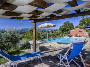 Monte San MartinoBelvilla by OYO La Priora的一个带蓝椅和遮阳伞的庭院和一个游泳池