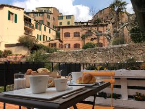 锡耶纳丰特盖亚之旅住宿加早餐旅馆的阳台上的桌子上配有咖啡杯和羊角面包
