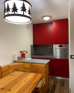 塞斯特雷Bilocale con vista a Sestriere的厨房配有木桌和红色橱柜。