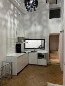 塞维利亚CASA ENEKO的厨房配有白色橱柜、水槽和吊灯。