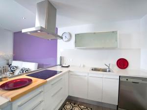 维耶亚高原Apartment Los Lirios-4 by Interhome的厨房配有白色橱柜和柜台上的红色盘子