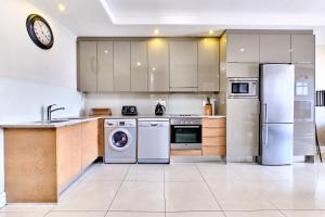 约翰内斯堡Comfort Apartment SA的厨房配有不锈钢用具和墙上的时钟
