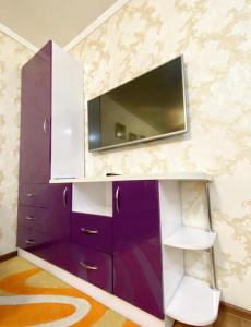 阿拉木图Apartments Ahmetova 4 21的紫色橱柜,墙上配有电视