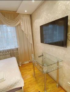 阿拉木图Apartments Ahmetova 6 32的一间设有玻璃桌和墙上电视的房间