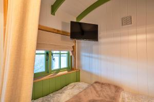 比沃辛Finest Retreats - The Shepherd's Hut at Northcombe Farm的一间卧室设有一张床、一台电视和一个窗口。
