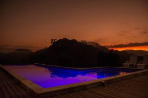 库尼亚Casarão com piscina e cachoeira CUNHA SP的日落时分拥有蓝色灯光的游泳池
