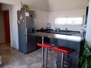 马拉圭Mi casa es tu casa!!的厨房配有不锈钢冰箱和红色凳子