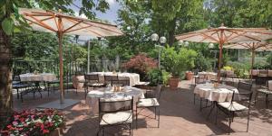 布拉格布拉格市NH酒店的花园内带桌子和遮阳伞的庭院