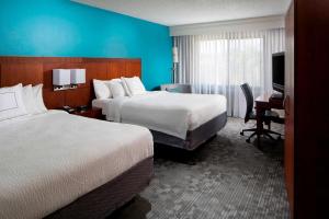 布卡拉顿Sonesta Select Boca Raton Town Center的酒店客房设有两张床、一张桌子和一台电视。