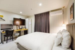 釜山Brown-Dot Hotel Minam的一间酒店客房,配有一张白色的床和一张书桌