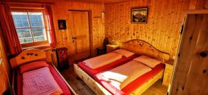 圣莱奥纳尔多因帕西里亚Almgasthaus Flecknerhütte的木制客房内的一间卧室配有两张床