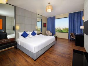 印多尔Essentia Luxury Hotel Indore的卧室配有带蓝色枕头的大型白色床