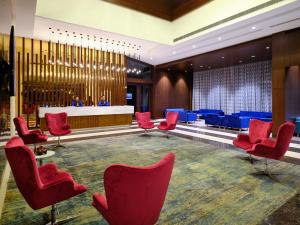 印多尔Essentia Luxury Hotel Indore的一间设有红色椅子和蓝色桌子的等候室
