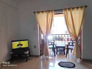 卡兰古特2 bhk Calangute - Baga road Saldanha Kyle Gardens的一间带电视、桌子和窗户的客厅