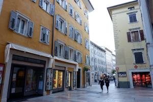 特伦托MUROS - Design Apartments in Trento的两个人沿着建筑物旁边的街道走