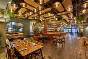 约翰内斯堡voco Johannesburg Rosebank an IHG Hotel的一间带木桌椅的餐厅和一间酒吧