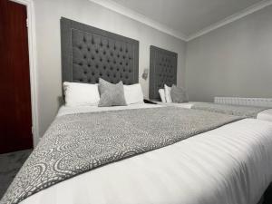 布莱克浦公园别墅酒店的一间卧室配有两张带白色床单和枕头的床。