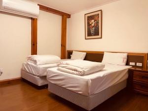 台东龙星花园度假木屋的配有白色床单的客房内的两张床