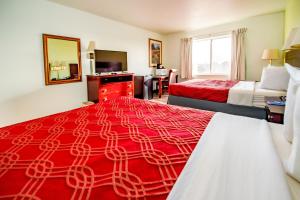 科罗拉多斯普林斯Rodeway Inn Central Colorado Springs的酒店客房带两张床和红色毯子