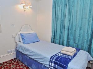 阿伯丁Brentwood Villa Bed and Breakfast的一间小卧室,配有一张带蓝色窗帘的床