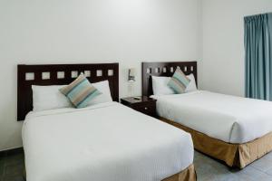 普拉亚卡门Almarea Vacation Condo的配有白色床单的酒店客房内的两张床