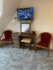 因弗内斯Royston Guest House Inverness的客房设有一张桌子、一台电视和两把椅子