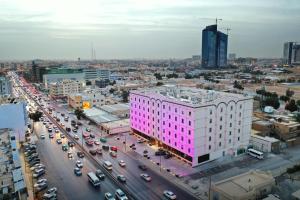 利雅德Hayat Al Riyadh Washam Hotel的城市街道上一座粉红色的建筑,交通繁忙