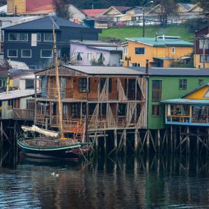 卡斯特鲁Hostal Palafito Waiwen的水面上的一群房子和一艘船