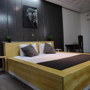 阿比让La Maison de Kouadio的一间卧室配有一张带枕头的大型木制床。