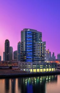 迪拜达玛克梅森运河景公寓式酒店的一座大建筑,在城市前的夜晚