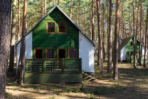 LubiatówSława Family Resort的树林中一座绿色和白色的小房子