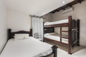 麦德林3H HOTEL Av 70的卧室配有2张双层床和白色床单
