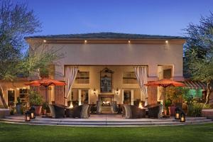 斯科茨Sonesta Suites Scottsdale Gainey Ranch的一个带椅子和遮阳伞的庭院