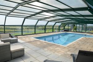 赫尔斯顿Tregaddra Farm B&B的一座带玻璃屋顶和游泳池的泳池房屋