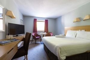 威廉堡加里多涅酒店的酒店客房配有一张床、一张书桌和一台电视。
