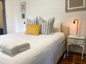 滕特菲尔德Blue Duck Cottage Village Comfort with Fireplace的卧室配有带条纹枕头的白色床