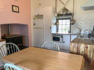 滕特菲尔德Blue Duck Cottage Village Comfort with Fireplace的一间带木桌的厨房和一间带炉灶的厨房