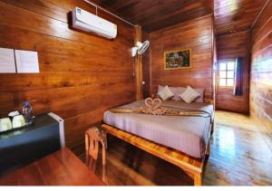 素可泰Perfect Resort Sukhothai & motorbikes for rent & bicycles for rent的木制客房内的一间卧室,配有一张床