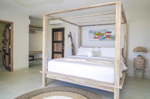 纳闽巴霍Theodor at Labuan Bajo的卧室配有带白色床单的木制天蓬床
