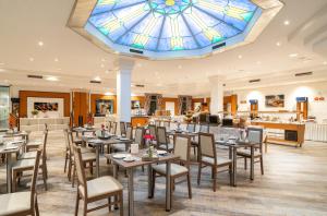博尔库姆博尔库姆诺德希酒店的一间带桌椅的用餐室和彩色玻璃天花板