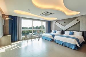 西归浦市Elren Hotel Jeju的酒店客房带两张床和一张桌子以及椅子。