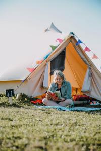 瓦伊河畔海伊Glamping at Hay Festival的坐在帐篷前读书的女人