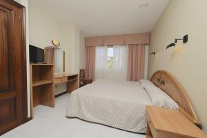 格罗韦帕拉伊索玛丽索酒店的一间卧室配有一张床、一张书桌和一台电视