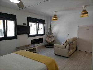 加的斯Acogedor apartamento en la playa de Cádiz的一间卧室配有一张床、一张沙发和一把椅子