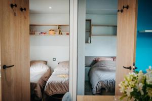 AubazinesMobil Home XXL 4 chambres - Camping Le Coiroux的一间卧室设有两张床和一个带镜子的门
